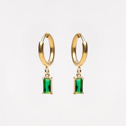 Gold hoop earrings with green gemstones on a white background